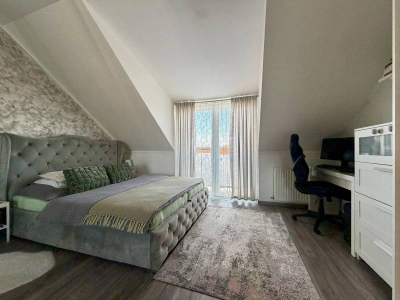 Schlafzimmer in einer 2-Zimmer-Wohnung mit Doppelbett, Schreibtisch und Boden mit Holzdekor.