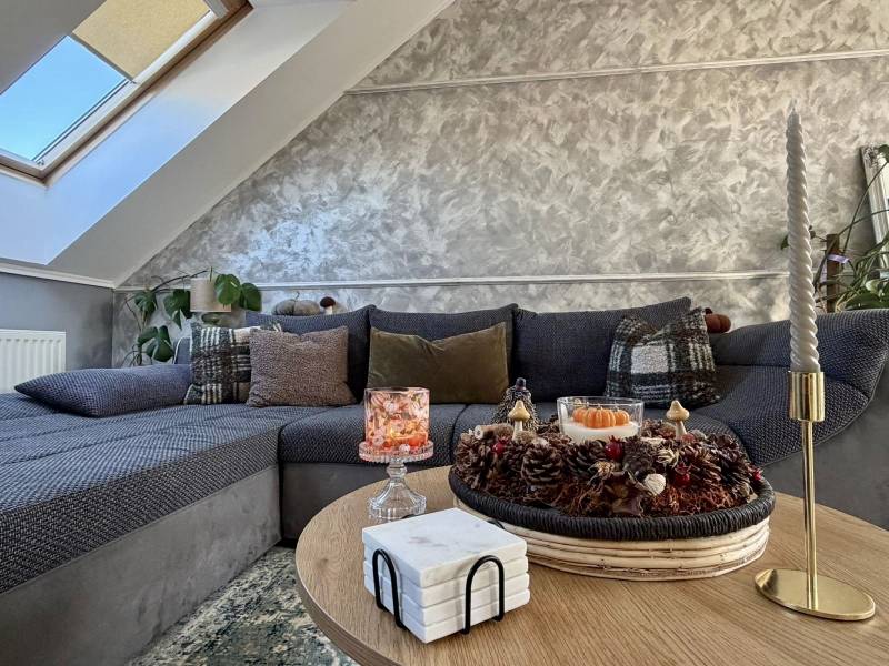 Wohnzimmer in einer Zweizimmerwohnung mit dekorativen Kissen auf dem Sofa und Kerzen auf dem Tisch.