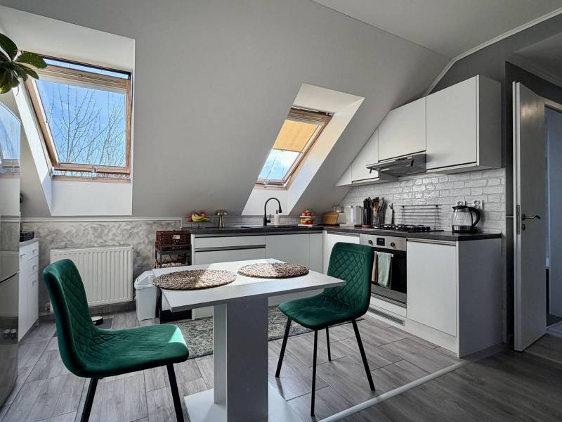 Küche in einer 2-Zimmer-Wohnung mit Holzboden und einem Tisch mit Stühlen.