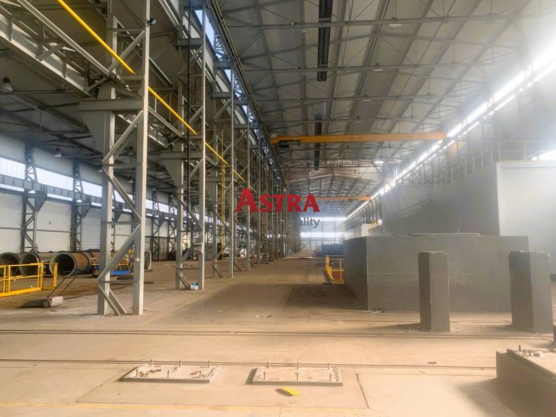 Produktionsräume mit Metallstrukturen und einem Kran innerhalb der Halle.