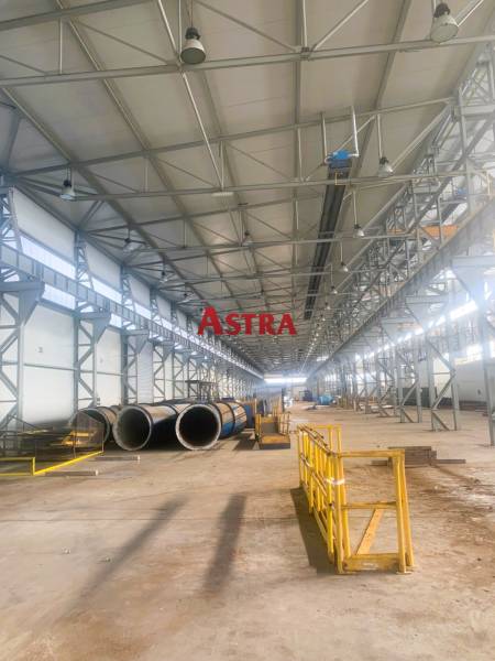 Produktionsräume mit Metallkonstruktionen und Rohrleitungen, Dobšiná. Breite Halle mit gelben Absperrungen.