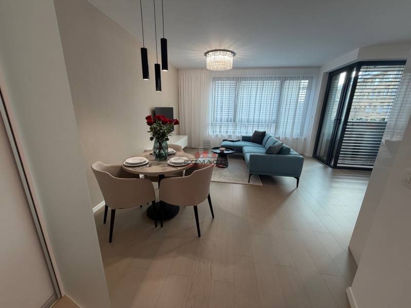 Innenraum einer 2-Zimmer-Wohnung mit Holzboden, Esstisch und Balkon.