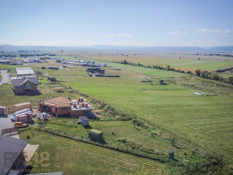 Grundstücke - Wohnen in Mlynica; im Bau befindliche Häuser und ausgedehnte Felder unter sonnigem Himmel.