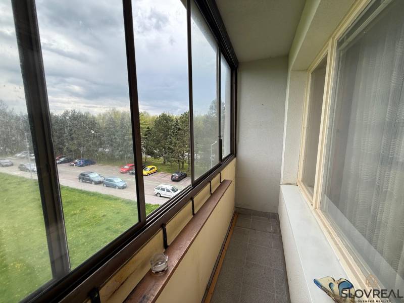 Balkon mit Glasverkleidung mit Blick auf den Parkplatz und Grünflächen in Detva, 3-Zimmer-Wohnung.