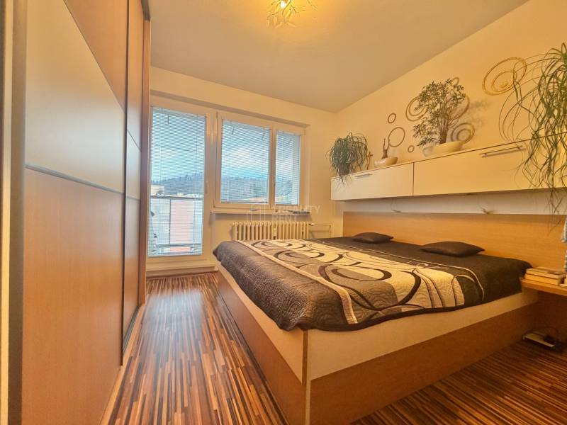 Schlafzimmer in einer 4-Zimmer-Wohnung mit Bett, Einbauschrank und Boden in Holzoptik.