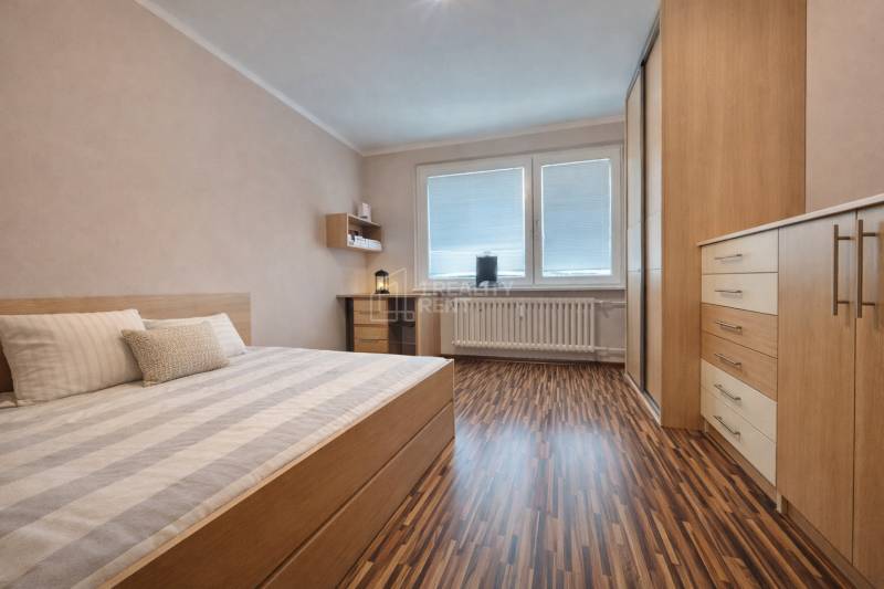 Schlafzimmer in einer 4-Zimmer-Wohnung mit Holzboden und Einbaumöbeln.