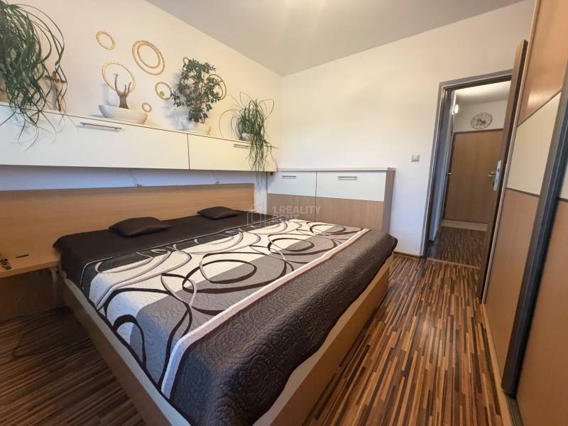 Schlafzimmer mit Einbauschränken und Bett in einer 4-Zimmer-Wohnung mit Holzdekor.
