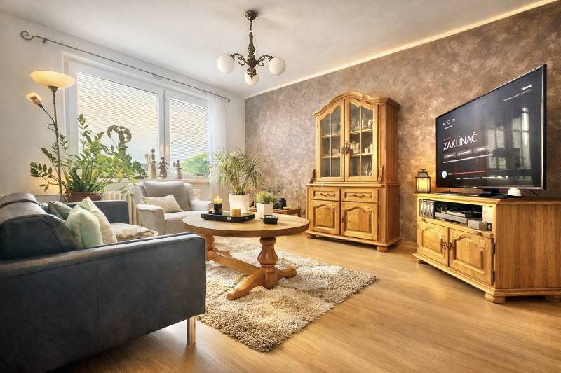 Wohnzimmer mit Sofa, Holzmöbeln und Boden mit Holzdekor in einer 4-Zimmer-Wohnung.