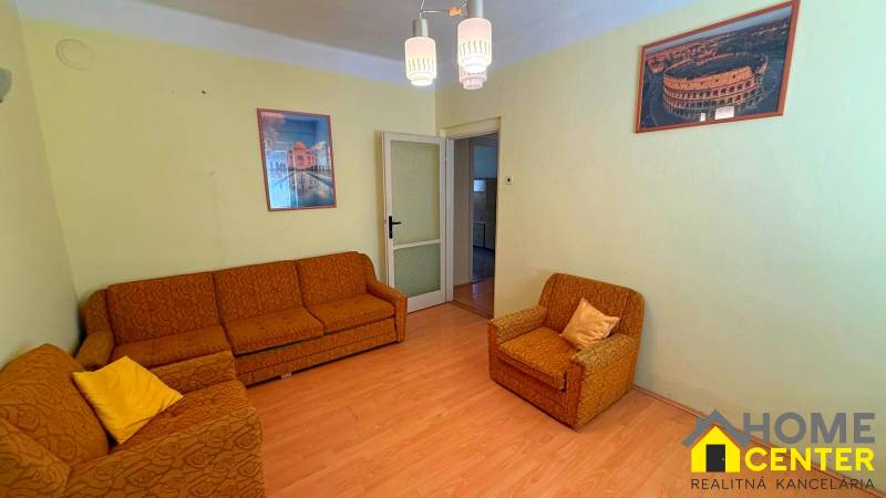 Wohnzimmer in einem Einfamilienhaus mit orangefarbenen Möbeln und einem Boden in Holzoptik.