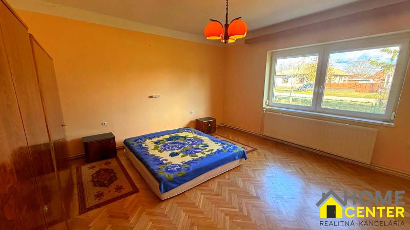 Ein Schlafzimmer in einem Einfamilienhaus mit einem Boden in Holzoptik und orangefarbenen Wänden.