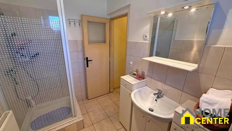 Badezimmer in einem Einfamilienhaus mit Waschbecken, Duschkabine und Fliesen.