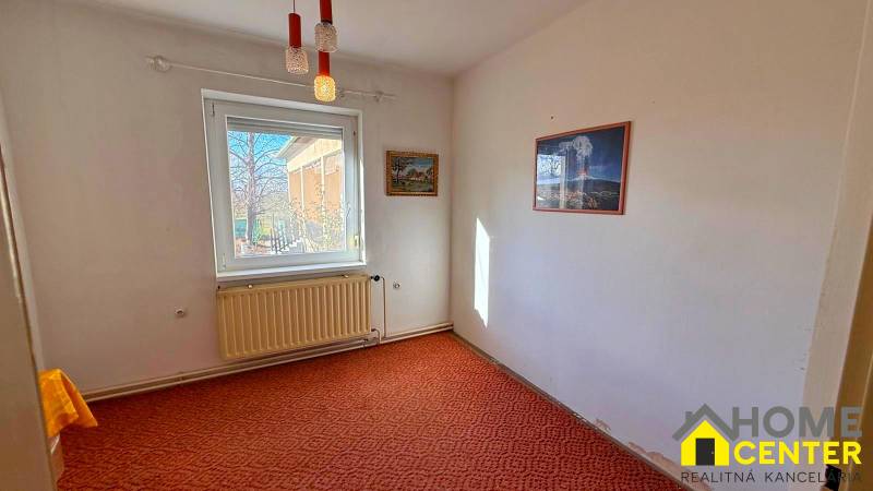 Ein Zimmer in einem Einfamilienhaus, mit Teppichboden, weißem Heizkörper, Bilder an den Wänden.