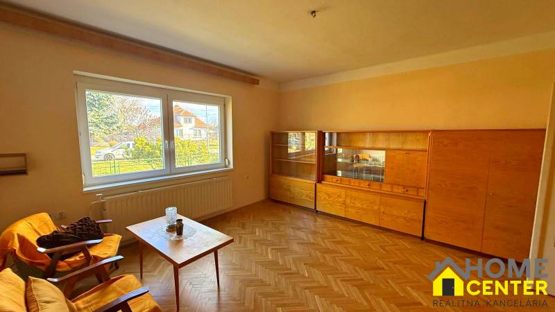 Wohnzimmer in einem Einfamilienhaus mit Möbeln und Boden in Holzoptik.