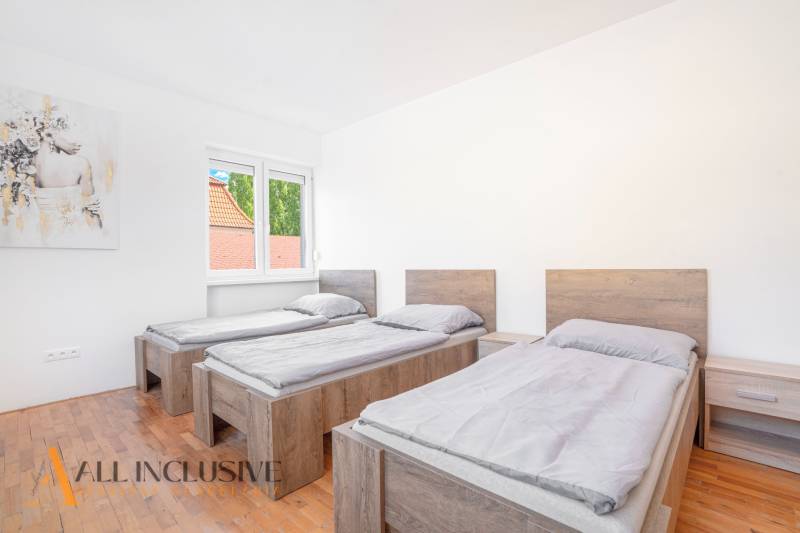 Drei Betten in einem Zimmer mit Holzboden und einem Bild an der Wand.