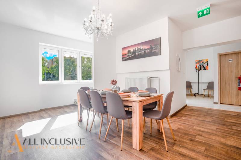 Ein Speisesaal mit einem Kronleuchter und einem Holzboden in einem Gebäude.