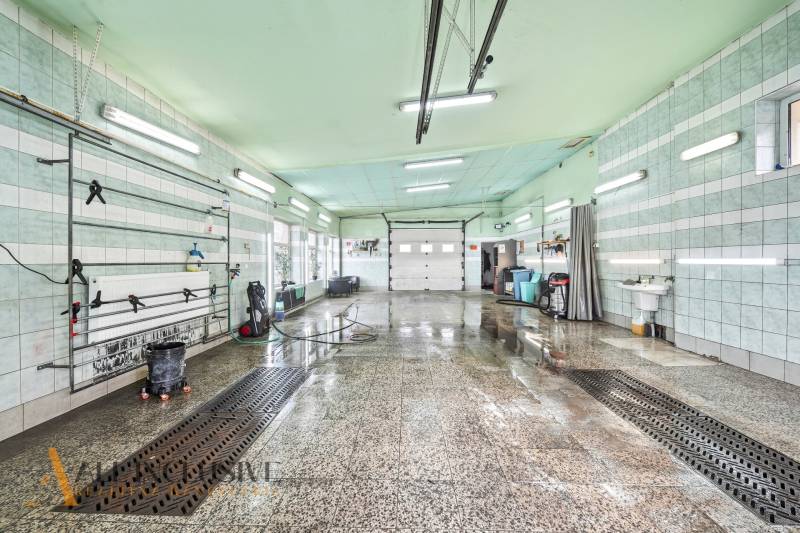 Innenwaschhalle mit nassem Boden und Leuchtstoffröhren an der Decke.