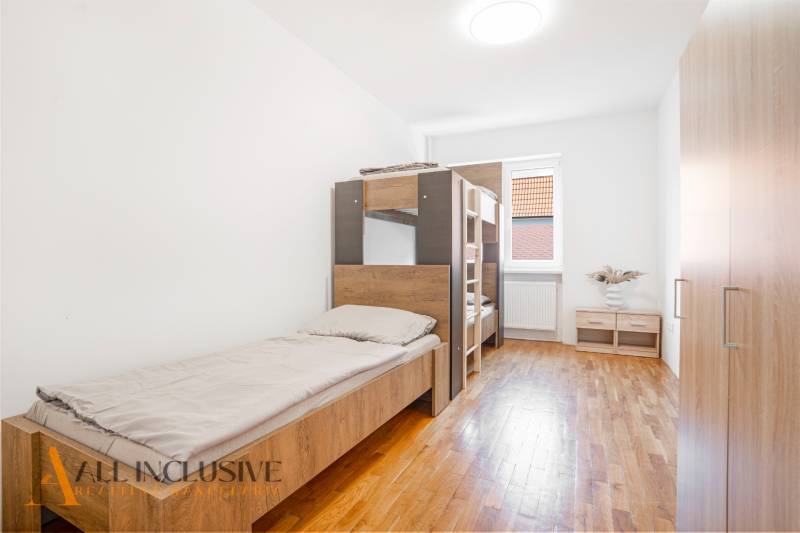 Das Innere eines Schlafzimmers in einem Gebäude mit Betten und einem Boden in Holzoptik.