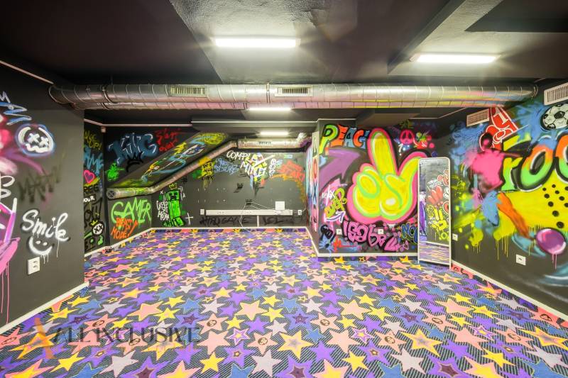 Innenraum eines Gebäudes mit Graffiti an den Wänden und einem bunten Teppich mit Sternen.