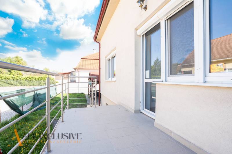 Ein Gebäude in Dunajská Streda mit Terrasse und Geländer, Himmel mit Wolken.