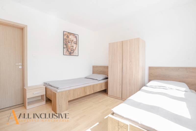 Schlafzimmer mit zwei Betten und Möbeln, Holzboden, Bild an der Wand.