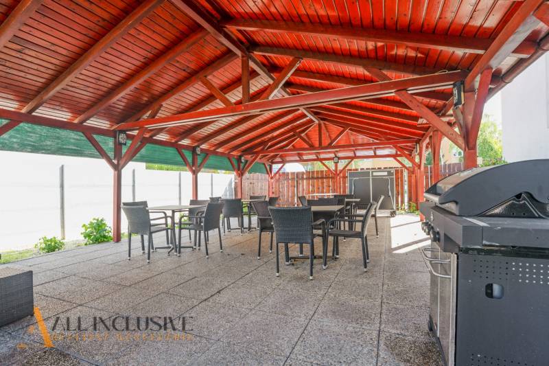 Außenterrasse eines Gebäudes in Dunajská Streda mit einem Holzdach und einem Grill.