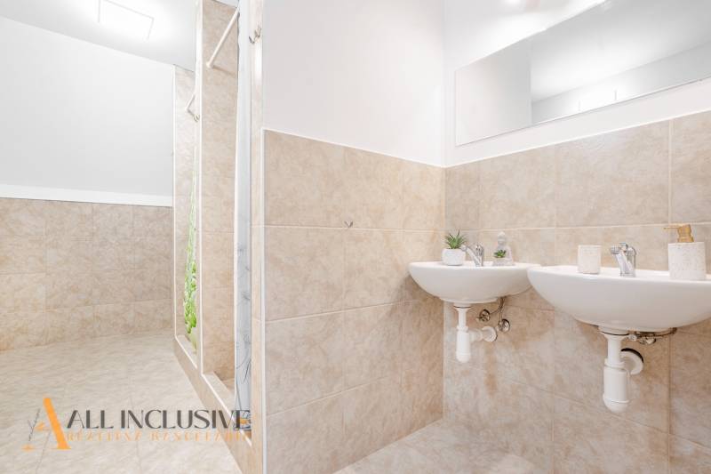 Badezimmer mit zwei Waschbecken und Dusche, dekorative Fliesen und Spiegel im Gebäude.