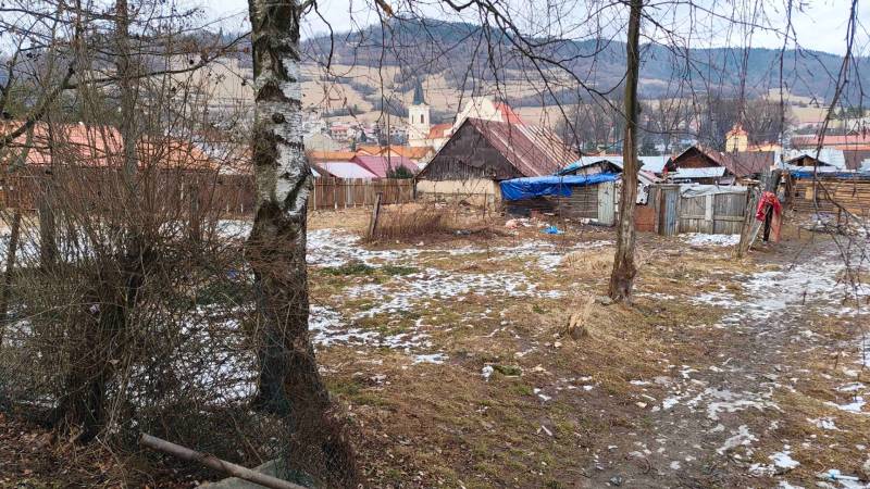 Verschneite Gärten in Nálepkovo mit Hütten und Blick auf die Hügel und die Kirche.