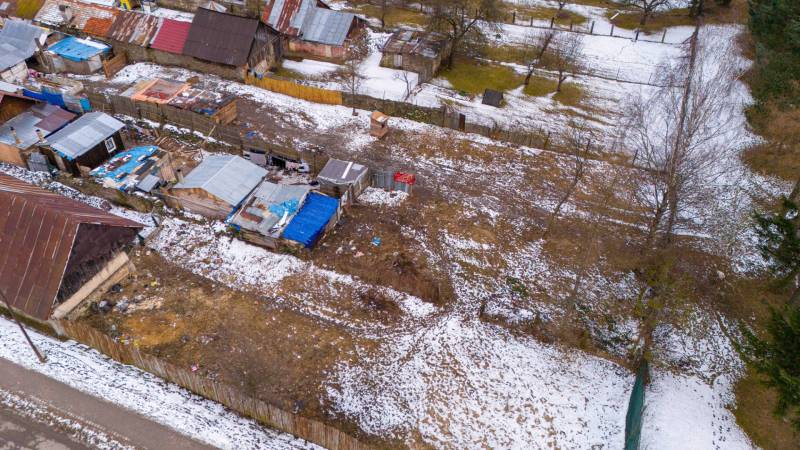 Wintergarten in Nálepkovo mit verschneiten Hütten und Bäumen, im Kontrast zum braunen Boden.