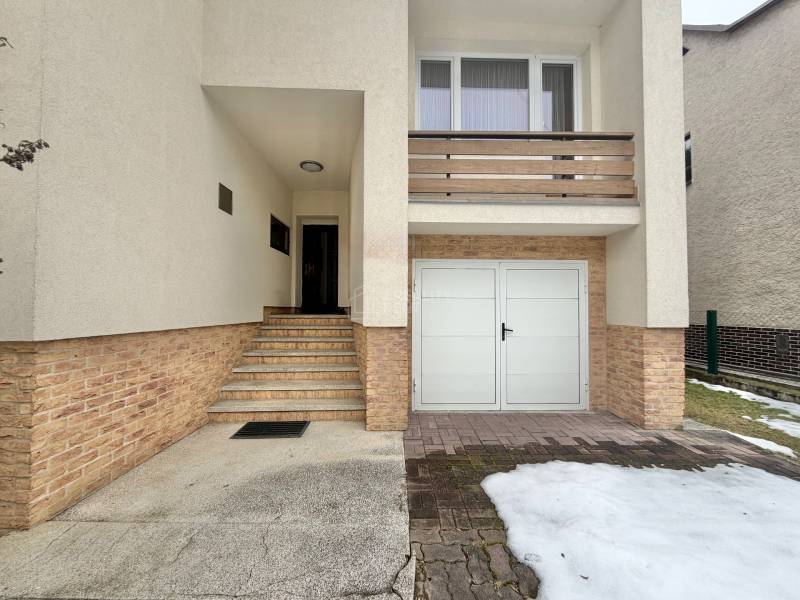 Ein Einfamilienhaus in Čadečka in Čadca mit Treppen und einer Garage, Schneereste auf der Zufahrtsstraße.