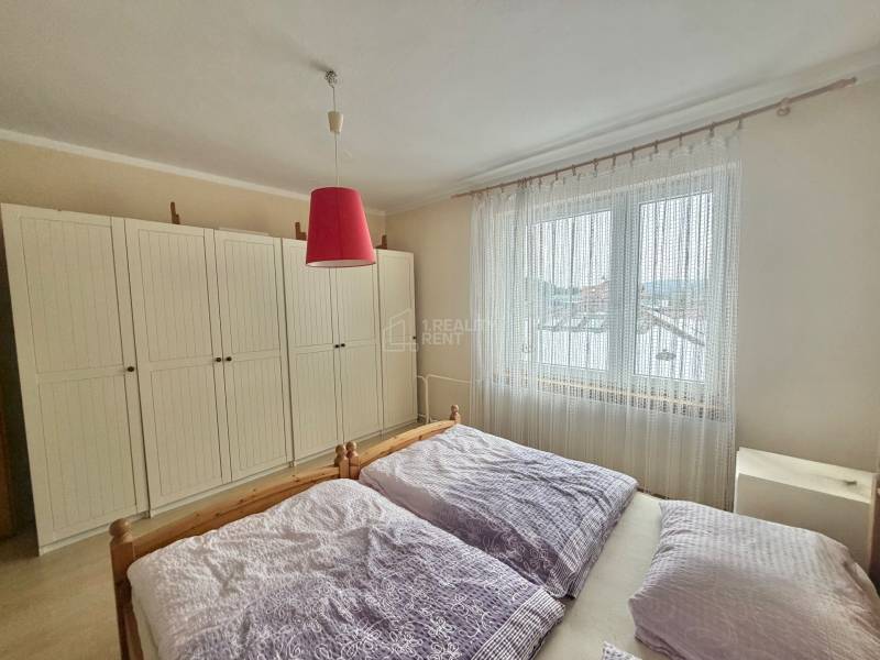 Schlafzimmer in einem Einfamilienhaus mit Bett, großem Schrank und Vorhängen.