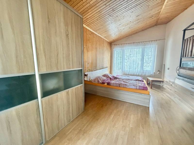 Schlafzimmer in einem Einfamilienhaus mit Holzboden, Bett und großem Fenster.