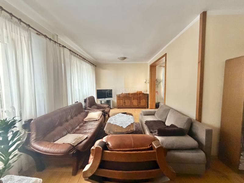 Wohnzimmer in einem Einfamilienhaus mit Holzboden, Sofa und Vorhängen.