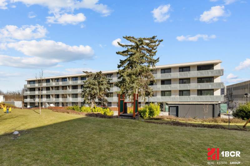 Ein Wohnhaus mit vier Stockwerken, umgeben von Rasen, Bratislava - Nové Mesto, Skalická cesta.