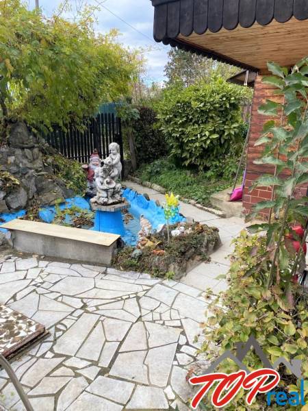 Der Garten des Ferienhauses im Košicer Stadtteil Vyšné Opátske mit einem Ziegelhäuschen und einer Statue.