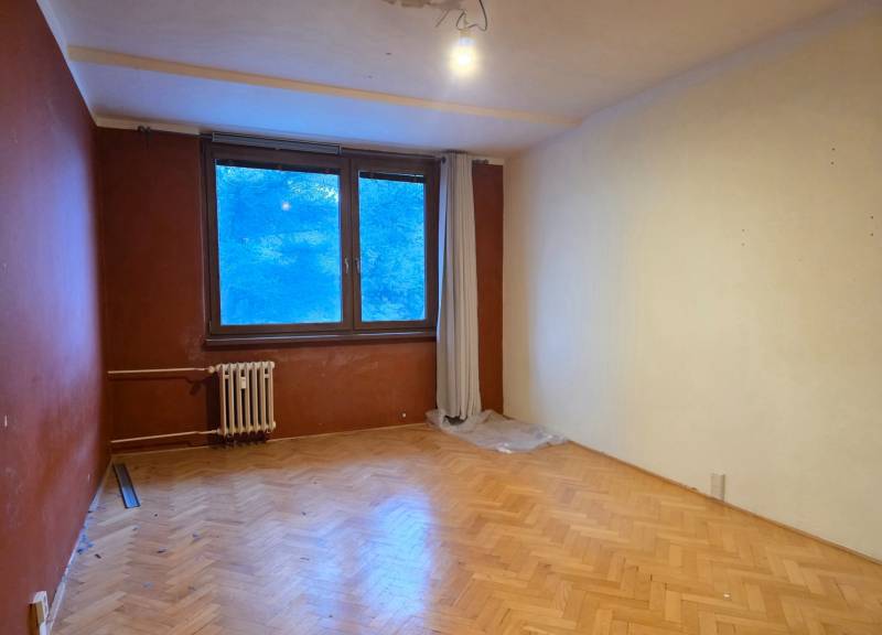 Ein Zimmer mit Holzboden und großem Fenster in einer 2-Zimmer-Wohnung.