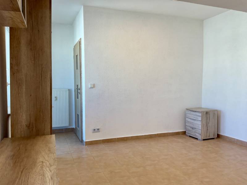 Weißes Interieur einer Einzimmerwohnung mit Fliesen und Holzelementen.