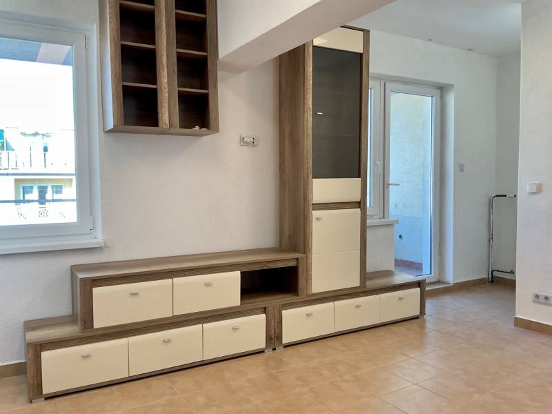 Wohnbereich in einer Einzimmerwohnung mit Möbeln und Keramikboden.