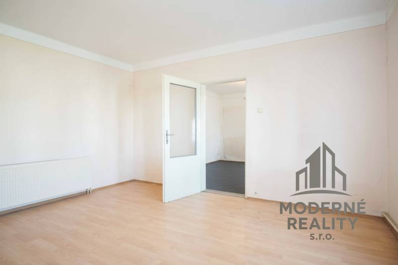 Ein Zimmer in einem Einfamilienhaus mit weißen Wänden und einem Boden in Holzoptik.