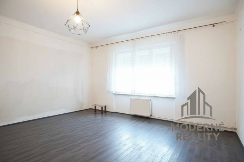 Ein Zimmer in einem Einfamilienhaus mit einem Boden in Holzoptik und einem großen Fenster.