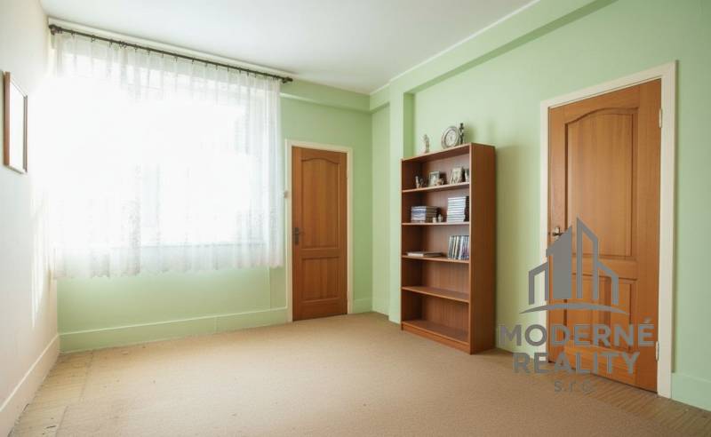 Ein Zimmer in einem Einfamilienhaus mit einer Bibliothek, grünen Wänden und Türen mit Holzdekor.