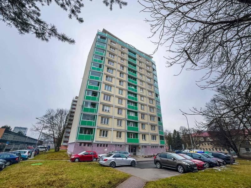 Hochhaus an der Straße SNP in Banská Bystrica mit einem Parkplatz im Vordergrund.