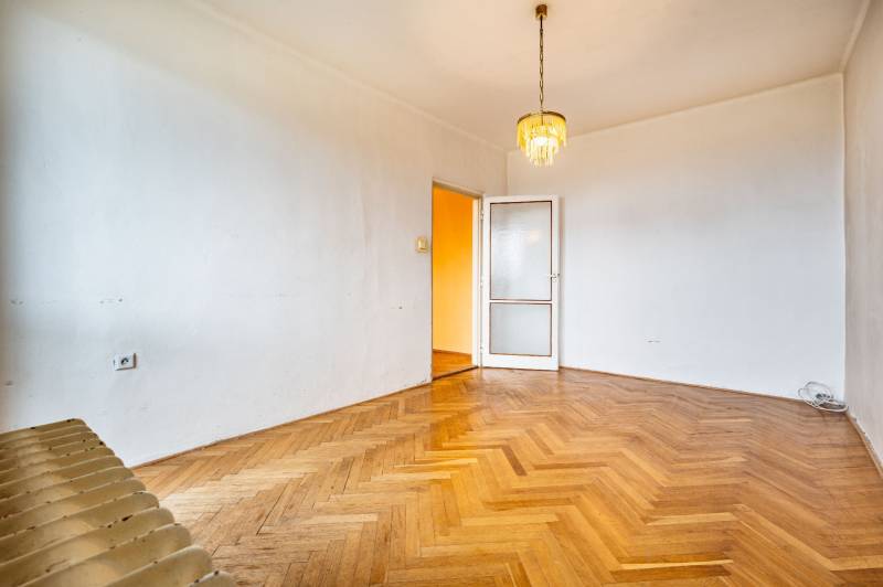 Ein leerer Raum mit einem Kronleuchter, einer Tür und einem Boden mit Holzdekor, eine 2-Zimmer-Wohnung.