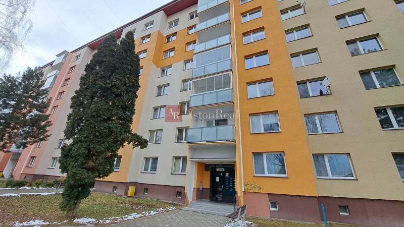 Ein siebenstöckiges Wohnhaus in der Straße Za dráhou in Ružomberok, umgeben von Bäumen.