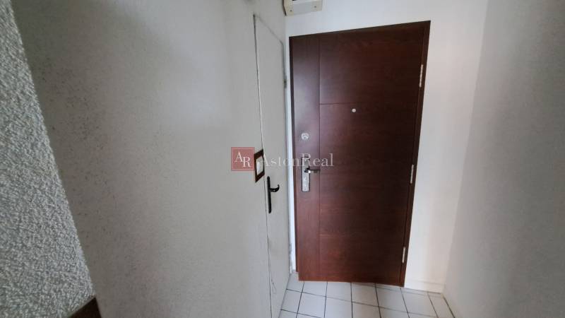 Eingangstür zu einer Einzimmerwohnung mit Fliesenboden und weißen Wänden.