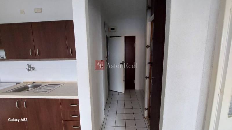 Küche mit dunklen Schränken und weißen Fliesen in einer Einzimmerwohnung.