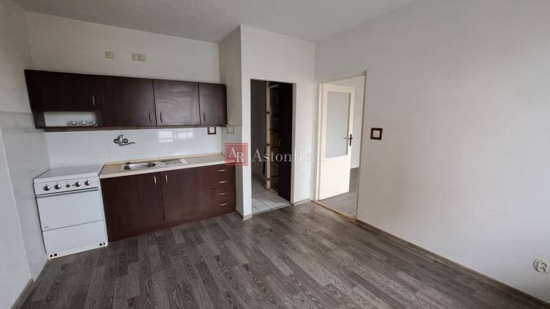 Küche mit dunklen Schränken und Holzboden in einer Einzimmerwohnung.