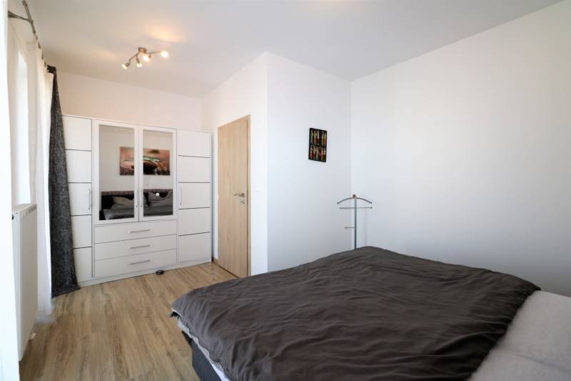 Schlafzimmer in einer 2-Zimmer-Wohnung mit Holzboden, Kleiderschrank und Bett.