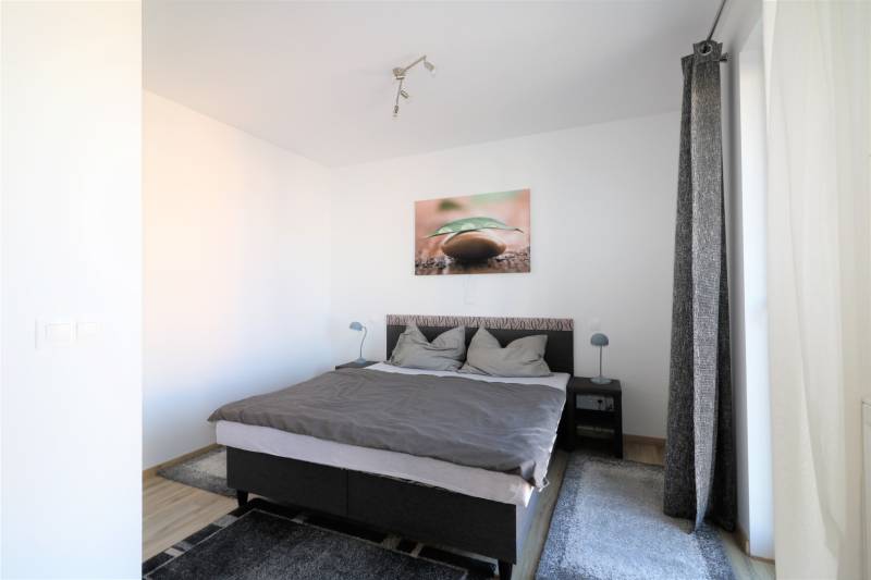 Helles Schlafzimmer in einer 2-Zimmer-Wohnung mit bequemem Bett und Teppich.