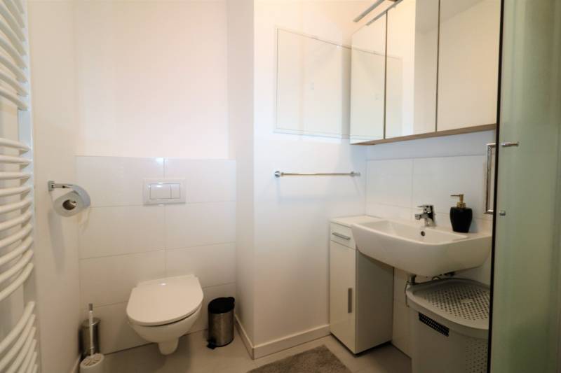 Badezimmer in einer 2-Zimmer-Wohnung mit Toilette, Waschbecken und Spiegelschrank.