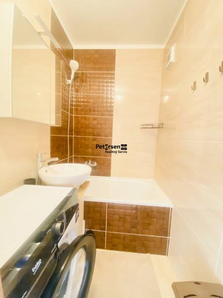 Badezimmer in einer 2-Zimmer-Wohnung mit Waschbecken, Badewanne und Waschmaschine.